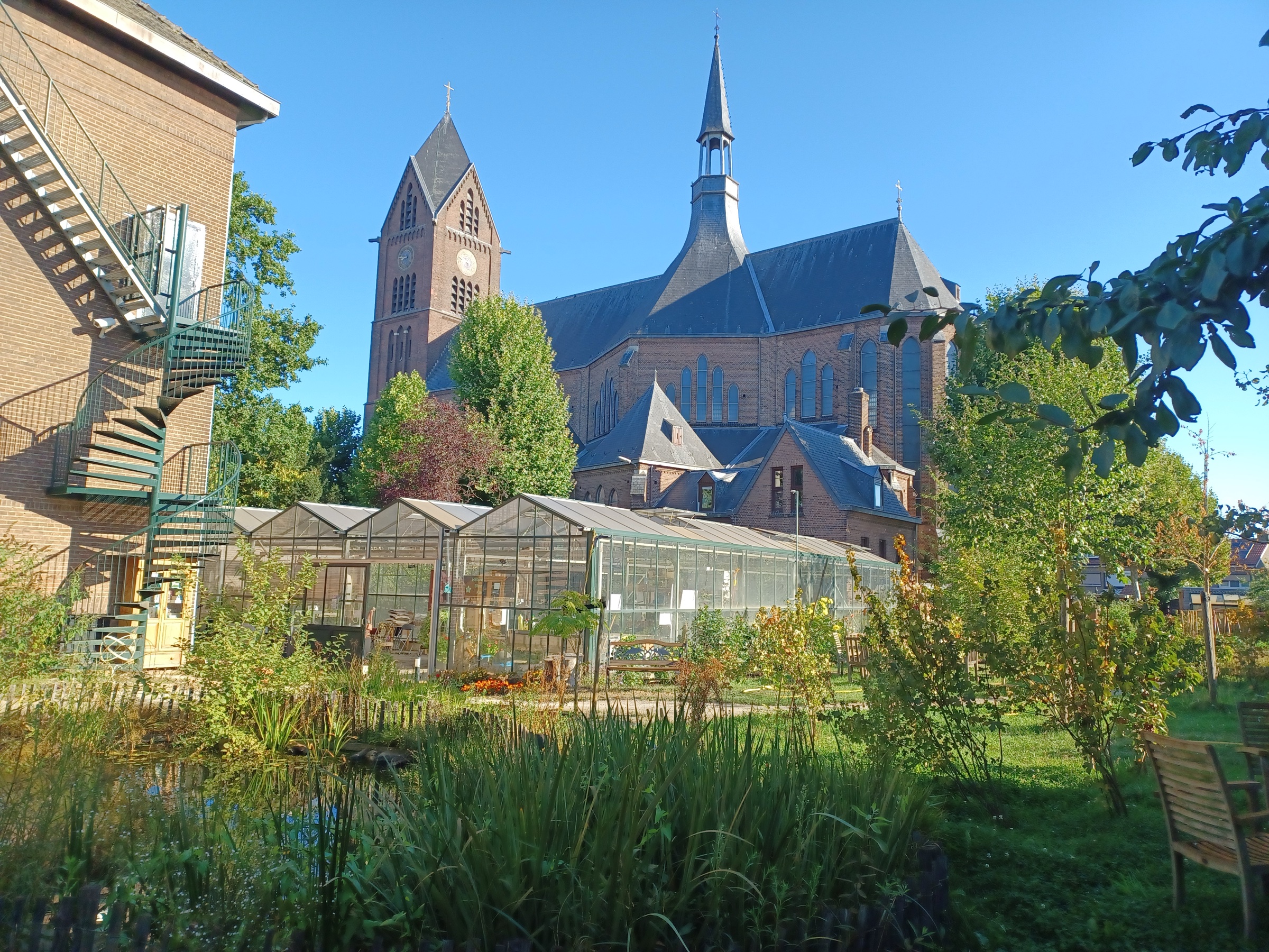 Ecologische Stadstuin Venlo Oud-Zuid met vijver en kas, voor de Onze Lieve Vrouwekerk